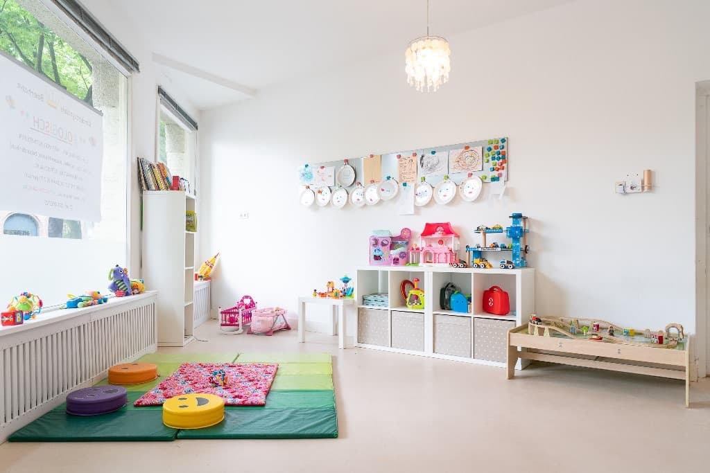 De lichte groepsruimte met speelkleed en speelgoed